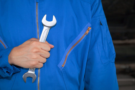 Man in blue technician uniform holding a wrench.