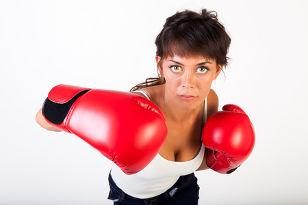 Young beautiful woman punching towards camera wearing boxing gloves on isolated white background - fitness and power conceptの写真素材