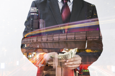 Double Exposure of Businessman in suit counting money and urban skyscrapersの写真素材