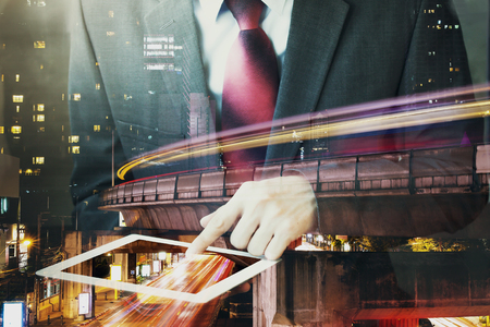Double Exposure of Businessman touching a tablet in long exposure city scene.の写真素材