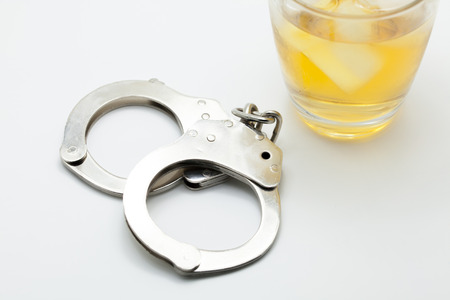 Glass of whiskey and handcuffs - Drinking law concept.の写真素材