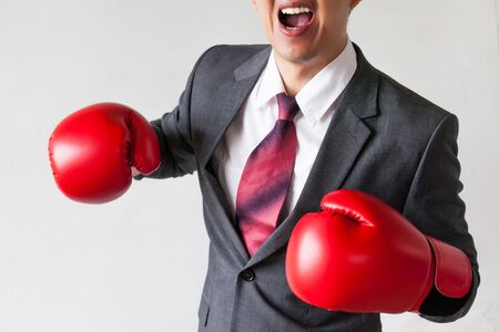 Businessman in boxing gloves launching a punch isolated on white backgroundの写真素材
