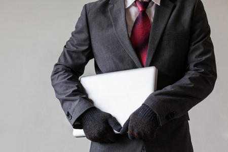 Man in suit is stealing a laptop - data or information, computer stealing conceptの写真素材
