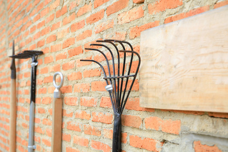 Agriculture and farming working tools hanging on red vintage brick wall (selective focus).の写真素材