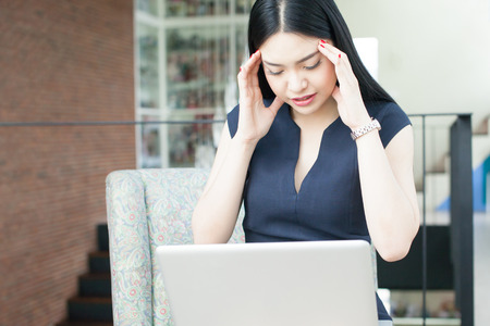 Beautiful Asian woman having headache while working.の写真素材