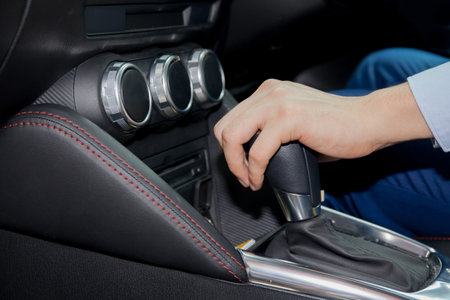 Human hand shifting automobile gear inside the car.
