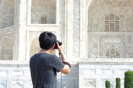 Close-up of Asian photographer on back taking pictures of Taj Mahalの写真素材