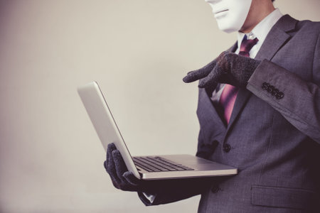 Business man in white mask wearing gloves and using computer - fraud, hacker, theft, cyber crime...
