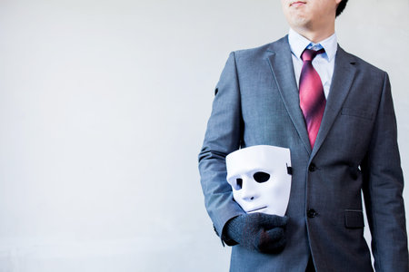 Business man carrying white mask to his body indicating Business fraud and faking business partnershipの写真素材