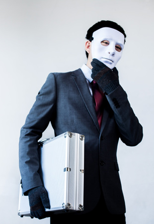 Businessman in disguise mask stealing a confidential suitcase.の写真素材