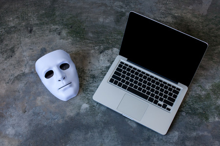 Anonymous mask to hide identity on computer laptop - internet criminal and cyber security threat concept.の写真素材