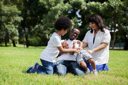Happy family having a good time and tickling a boy in the park.の写真素材