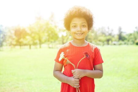 Happy Smiling African American girl holding flowers in park の写真素材
