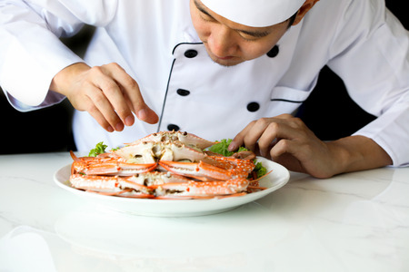 Asian chef preparing and decorating grilled crab seafood meal with vegetableの写真素材