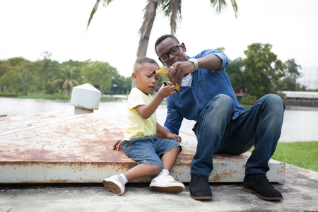 Happy African American father and son enjoying joyful moment together in the outdoor parkの写真素材