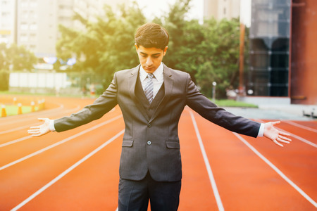 Business man spreading arms with confidence on the running trackの写真素材