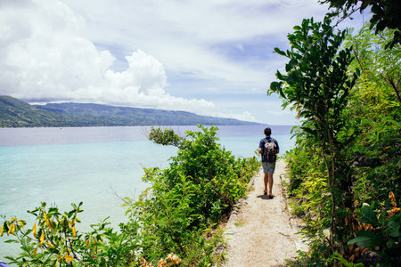 Back of backpacker walking and hiking on mountains and sea in tropical summer - with copyspace