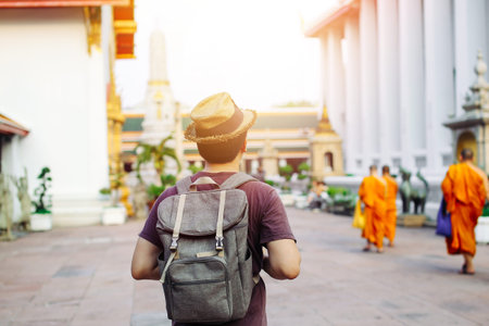 Young Asian traveling backpacker in Wat Pho with Buddhist monks walking background in Bangkok, Thailandの写真素材