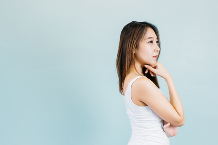 Attractive Asian woman thinking and arms crossed isolated on blue pastel backgroundの写真素材