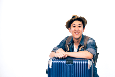 Young Asian tourist with hat smiling and putting arms on travelling luggage isolated over white backgroundの写真素材