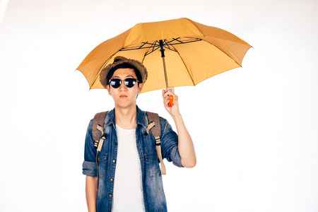 Young Asian tourist holding umbrella isolated over white background. Alone and Looking for partner to travelの写真素材
