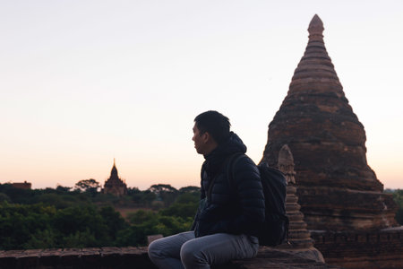 Silhouette of young travel man watching sunrise in temple pagoda area