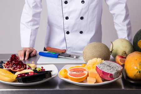 Chef preparing fruits for fruit salad over white backgroundの写真素材
