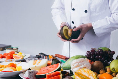 Chef preparing fruits for fruit salad over white background