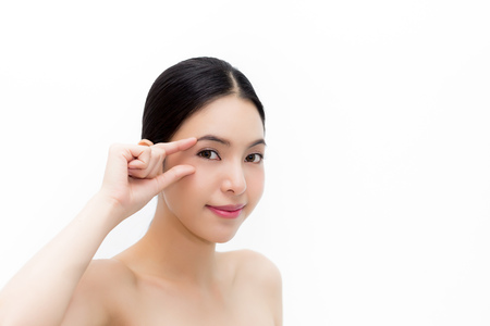 Young attractive woman in natural beauty condition gently touching eyes to focus on eyecare health isolated over white backgroundの写真素材