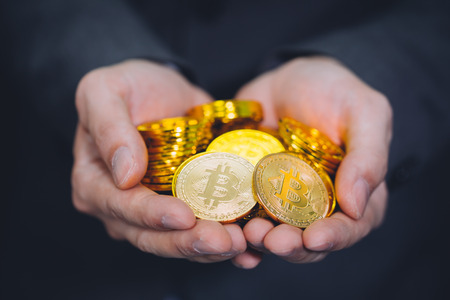 Close-up of businessman's hands full of bitcoin sign of coins - cryptocurrency financial trade wealth and business investment and blockchain technologyの写真素材