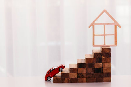 Toy car driving up towards the stairs of achievement with house on the top - big dream and growth achievement in buying house and propertyの写真素材