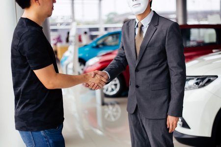 Dishonest and evil salesman in business suit in car dealership company handshaking welcome customers to exploit and deceive customers - fraud and bad quality service in business conceptの写真素材