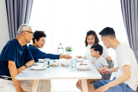 Happy Asian extended family having dinner at home full of laughter and happinessの写真素材