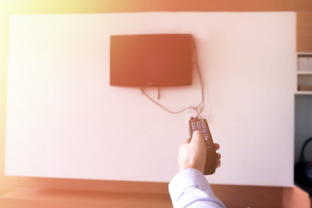 Human hand holding a remote controller to turn on and off the television