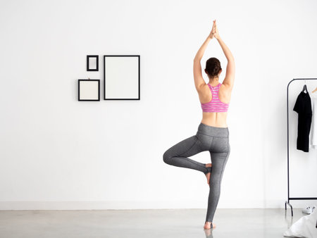 Back of Young beautiful caucasian sporty and active woman in sporty wear doing yoga position and...
