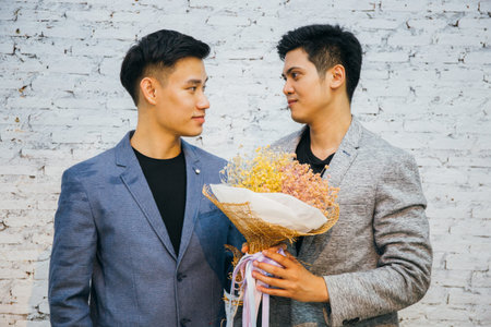 Gay couple holding a bouquet of flowers, ready to give to his partner for special occasions or...