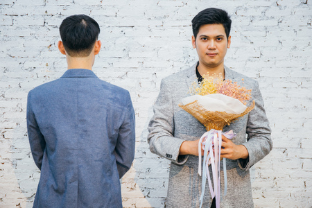 Gay couple holding a bouquet of flowers, ready to give to his partner for special occasions or wedding proposal. Asian homosexual men togetherの写真素材