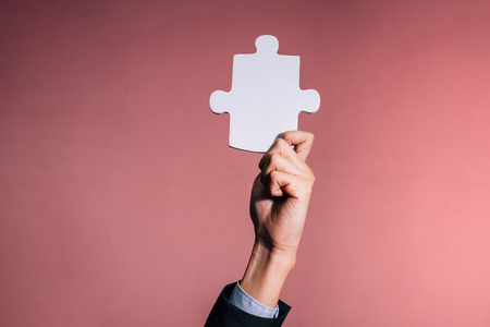 Business man giving the missing piece of jigsaw as offering a success, business solution in corporate partnership - with empty copy space to insert textの写真素材