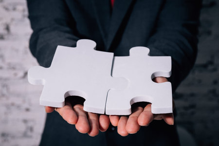 Business man giving the missing piece of jigsaw as offering a success, business solution in corporate partnershipの写真素材