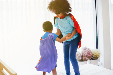 African American happy and confident young kids playing  and dressing up as superhero together in...