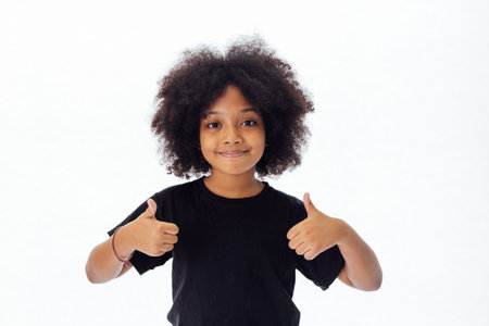 Adorable and cheerful African American kid with afro hairstyle giving thumbs up isolated over white...