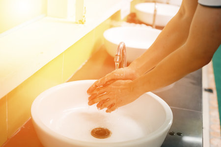 Close-up of human hands washing away germs and bacteria under the sanitary crane