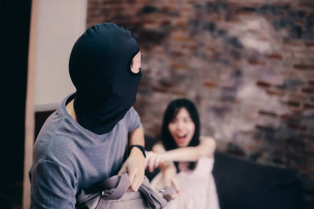 Anonymous criminal thief in hidden mask trying to snatch purse bag from young lady fighting each...