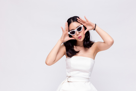 Elegant and attractive Asian chic fashion woman in stylish white dress with sunglasses in isolated backgroundの写真素材
