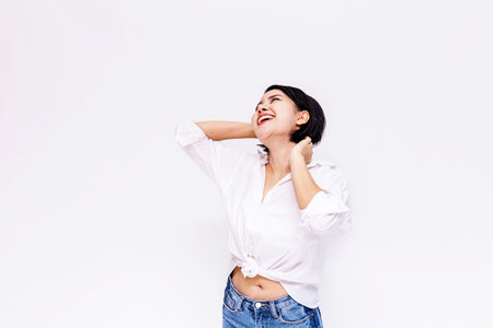 Young beautiful and confident Asian girl with short hair raising hands up with joy and happiness in...