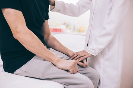 Physician doctor comforting a male patient in hospital roomの写真素材