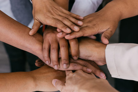 Close up of young business people putting their hands together for unity. Hands stacking over for...