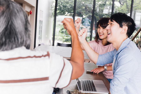 Casual and happy smiling Asian business casual people celebrating success and hands up having fun meeting togetherの写真素材