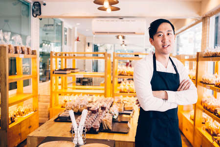 Young Asian male bakery shop merchant business owner smiling and looking at the camera in bread storeの写真素材