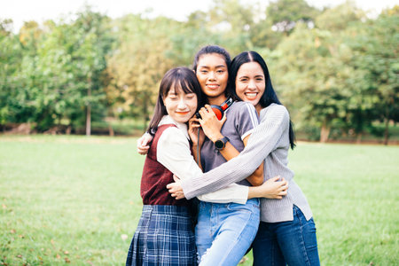 Portrait of multiracial and diverse all female teenage friends hugging and embracing together in the...